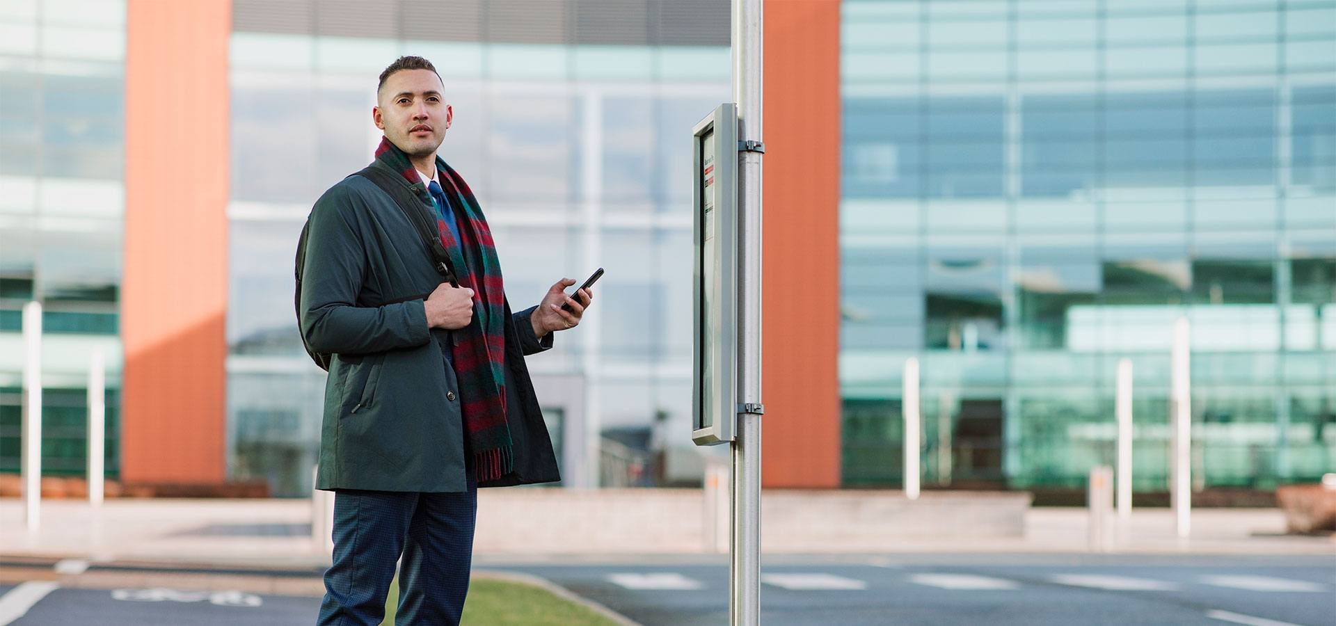 Man in front of building looking at his phone