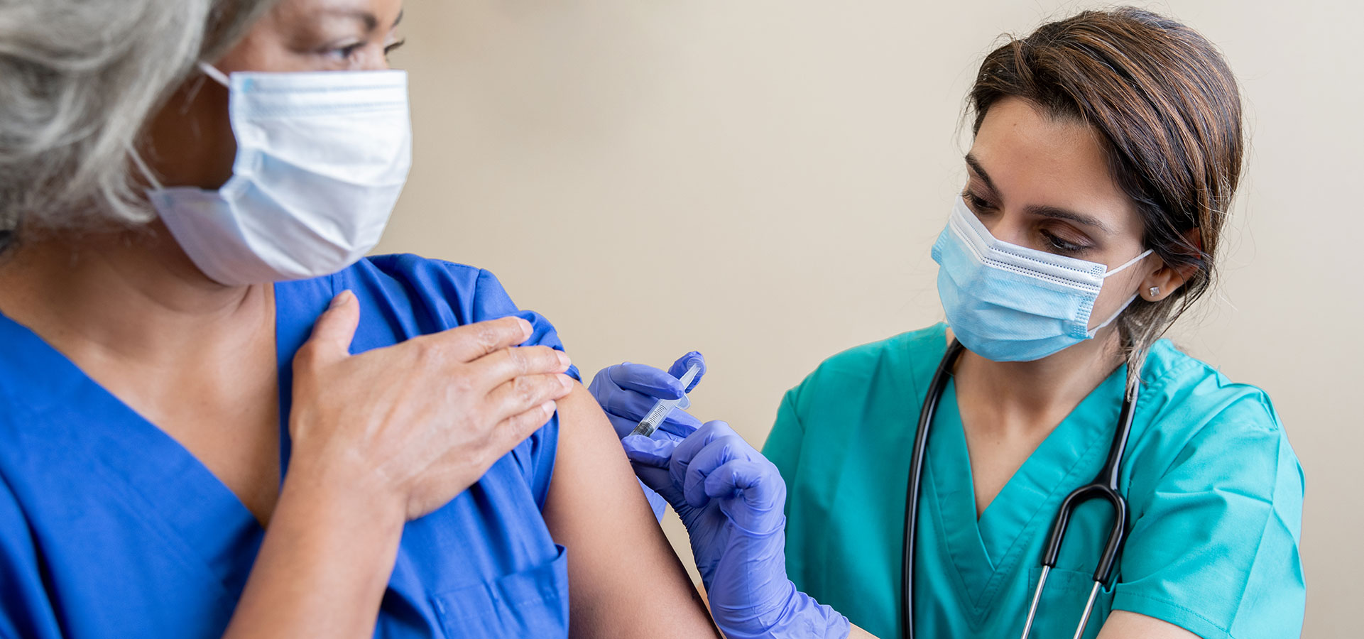 Nurse gives senior adult healthcare worker the Covid-19 vaccine