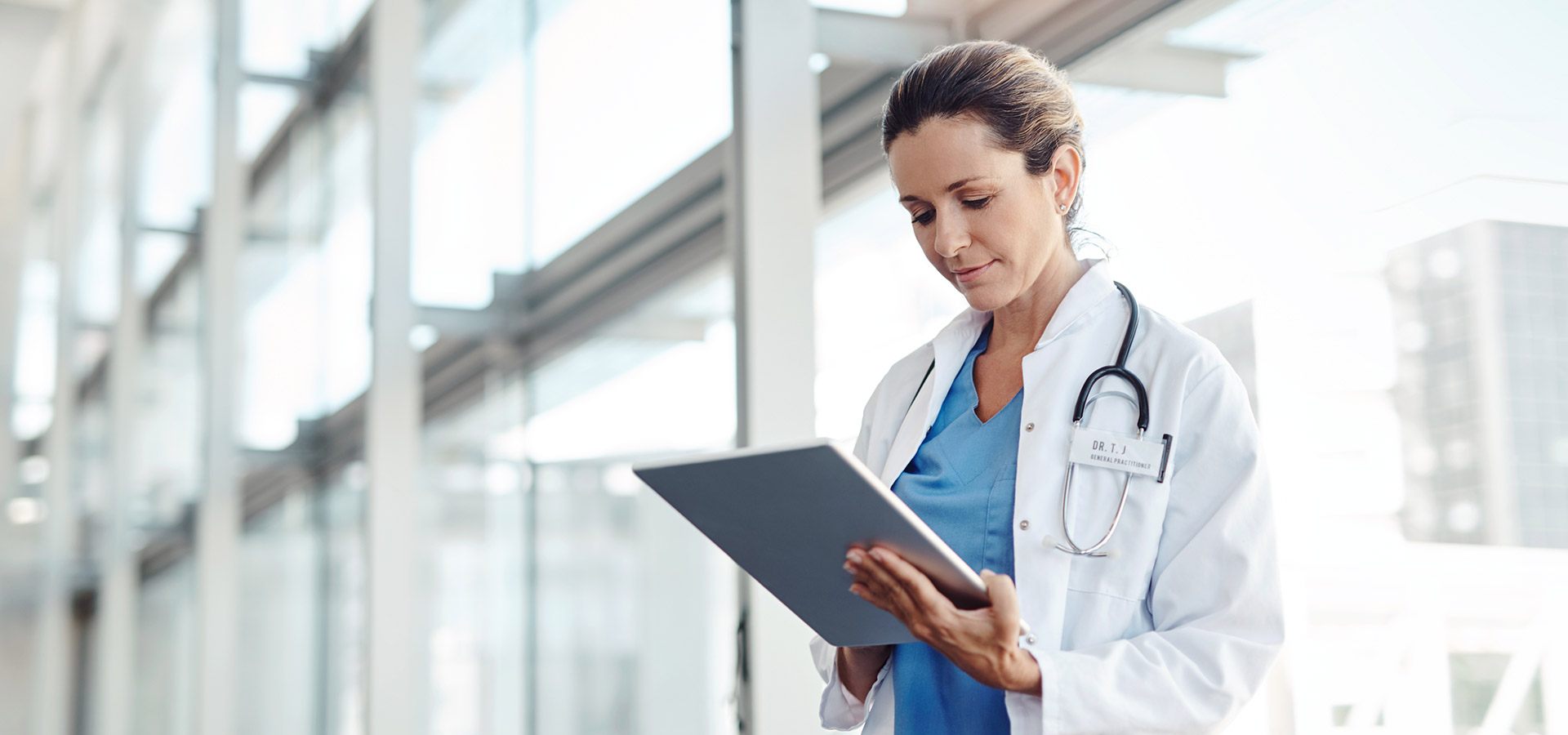 Woman in lab coat looking at a tablet