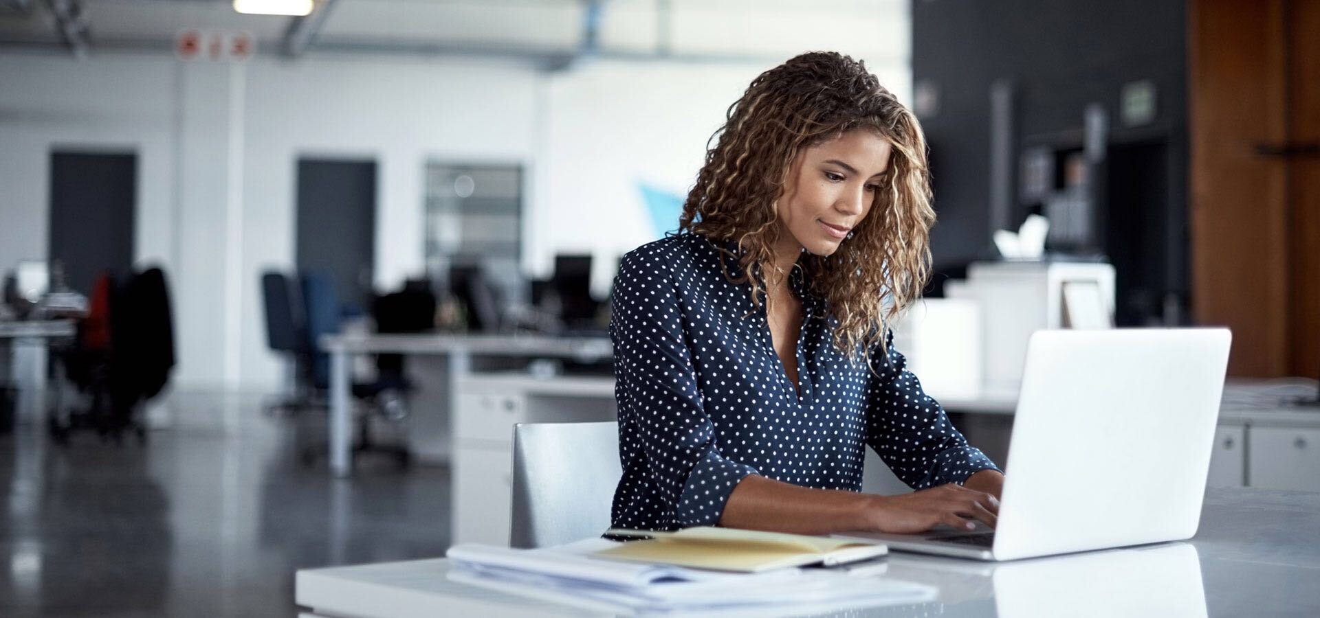 Woman using a laptop and surrounded by papers