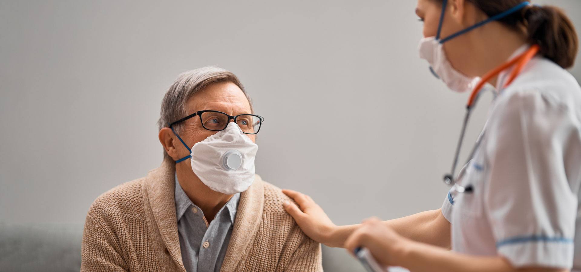 Doctor and man wearing facemasks in office