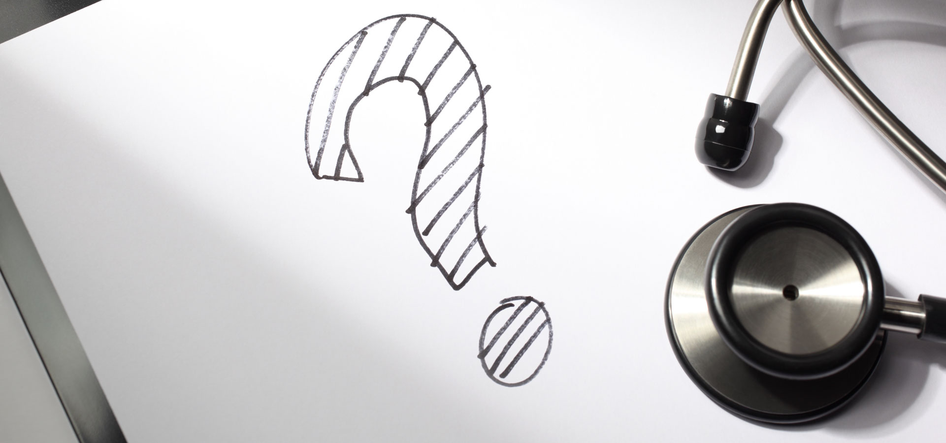 question mark drawn in marker on white paper next to stethoscope
