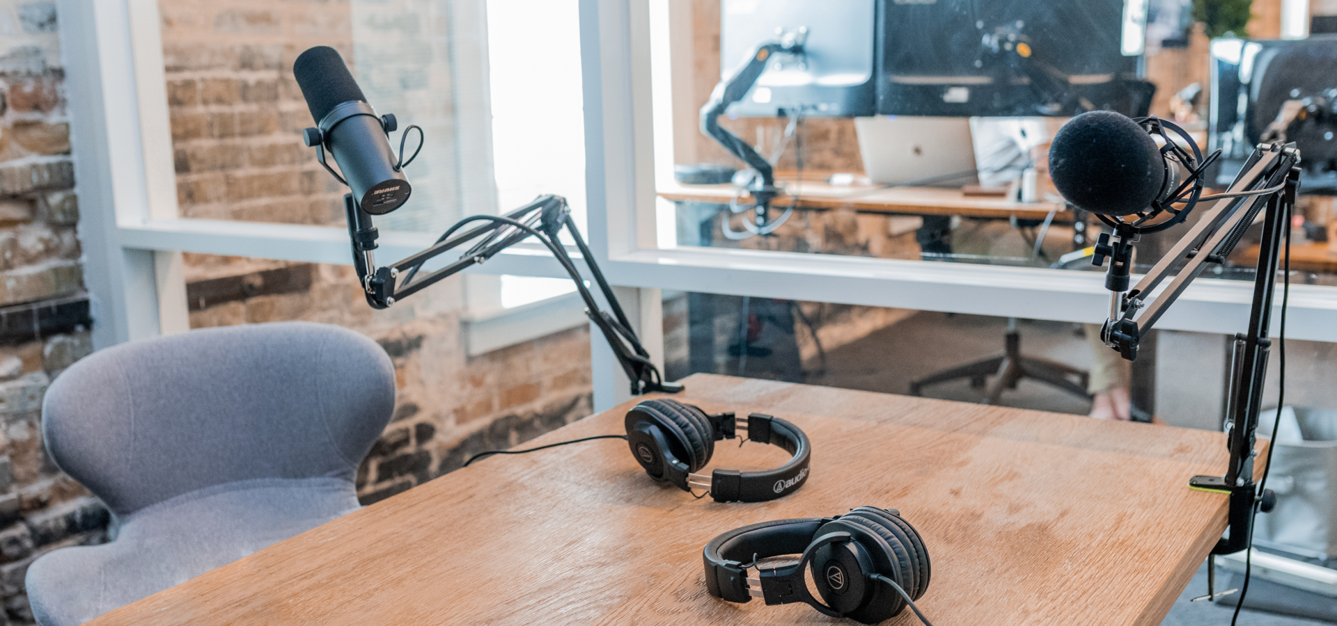 A pair of microphones and headsets on a desk in an empty studio.