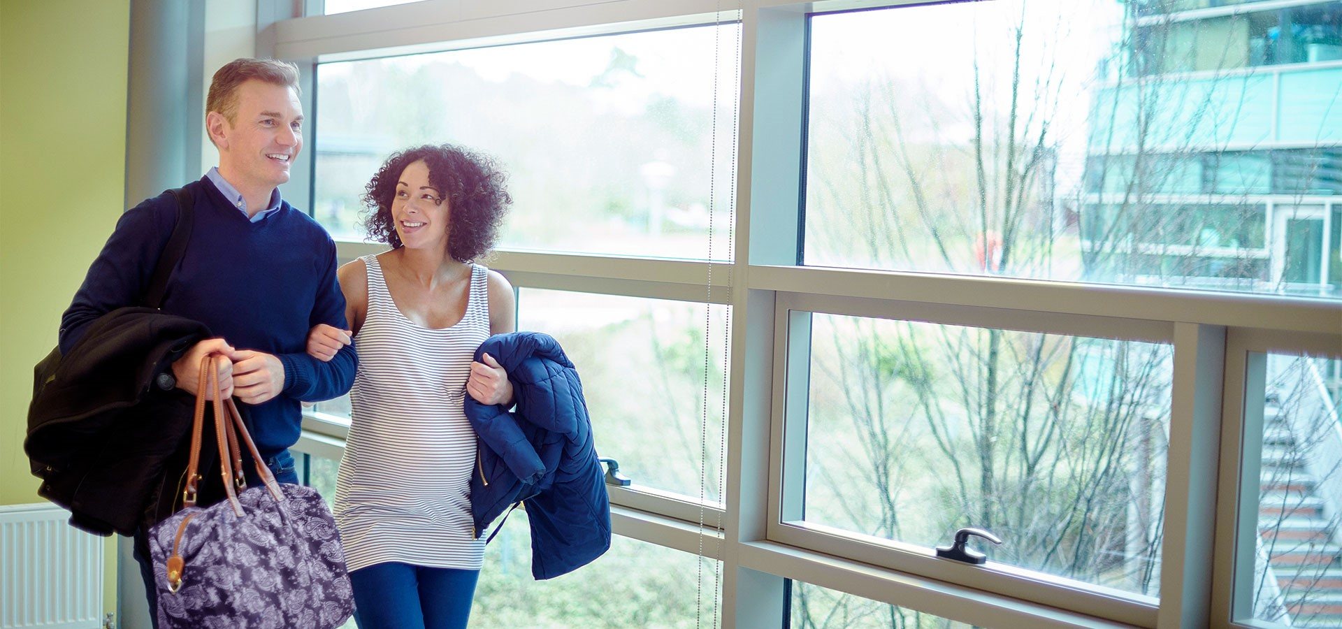 Man and woman walking in hospital with overnight bag