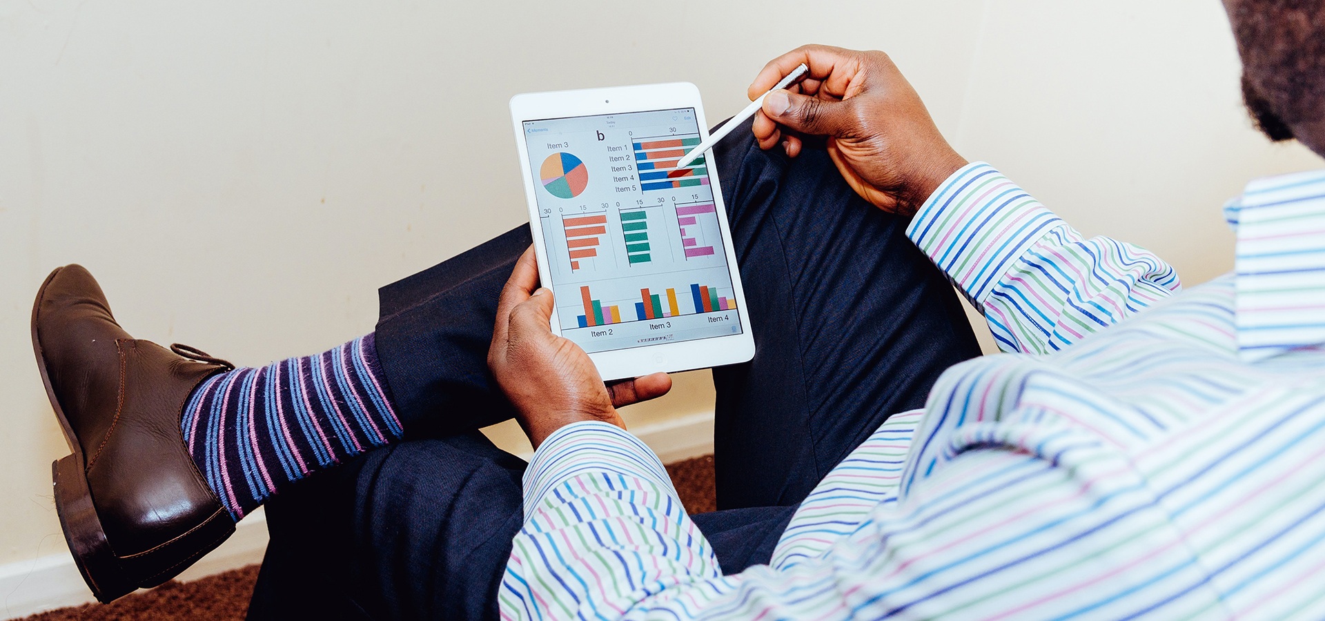 Person holding a tablet with graphs displayed on it.