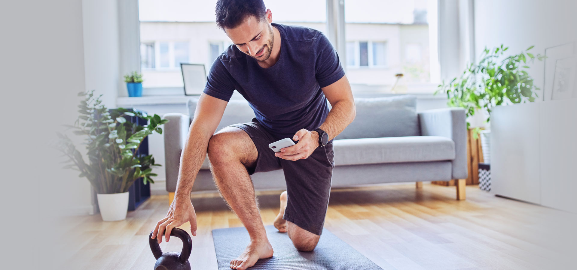 Person looking at phone and reaching for kettle bell weight