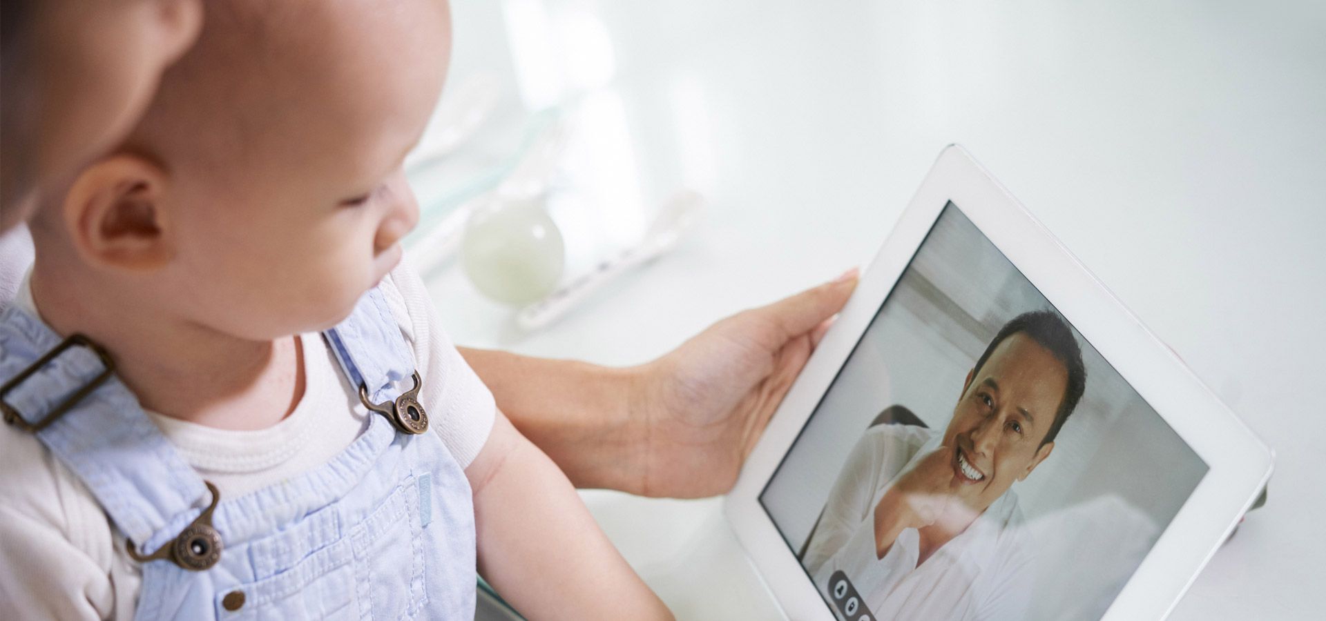 Child looks at a tablet with a person in a labcoat displayed