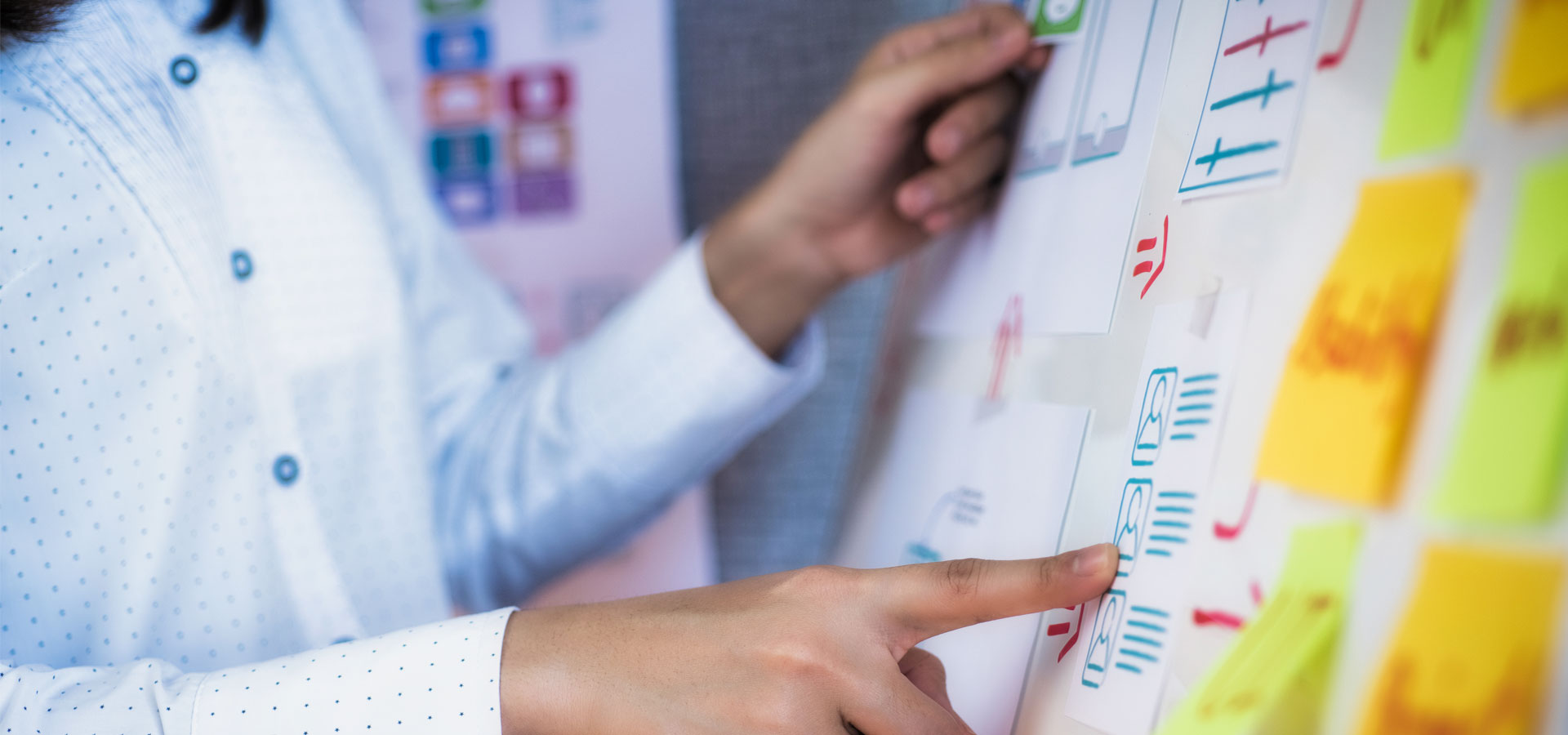 person pointing to a board with text and post it notes