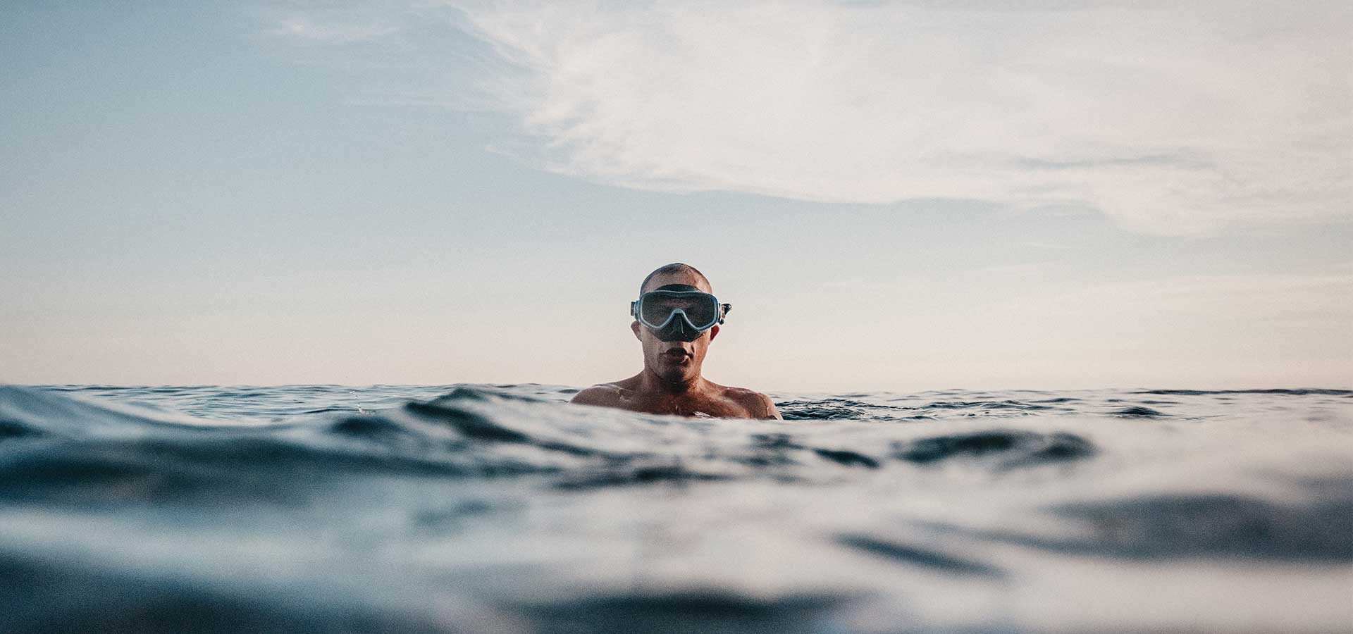 Man with swim mask in the middle of the ocean.