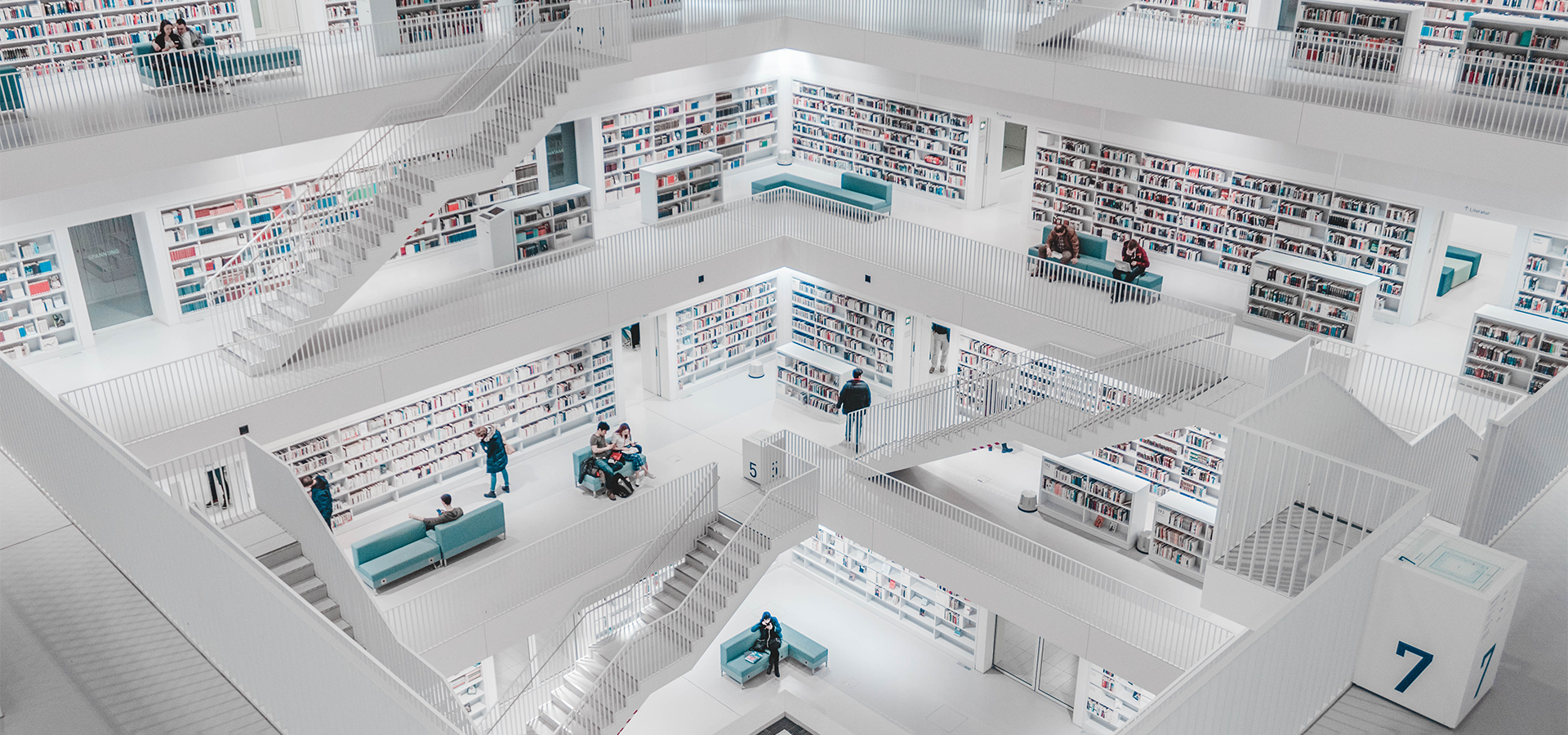 People standing inside white concrete building interior photo.