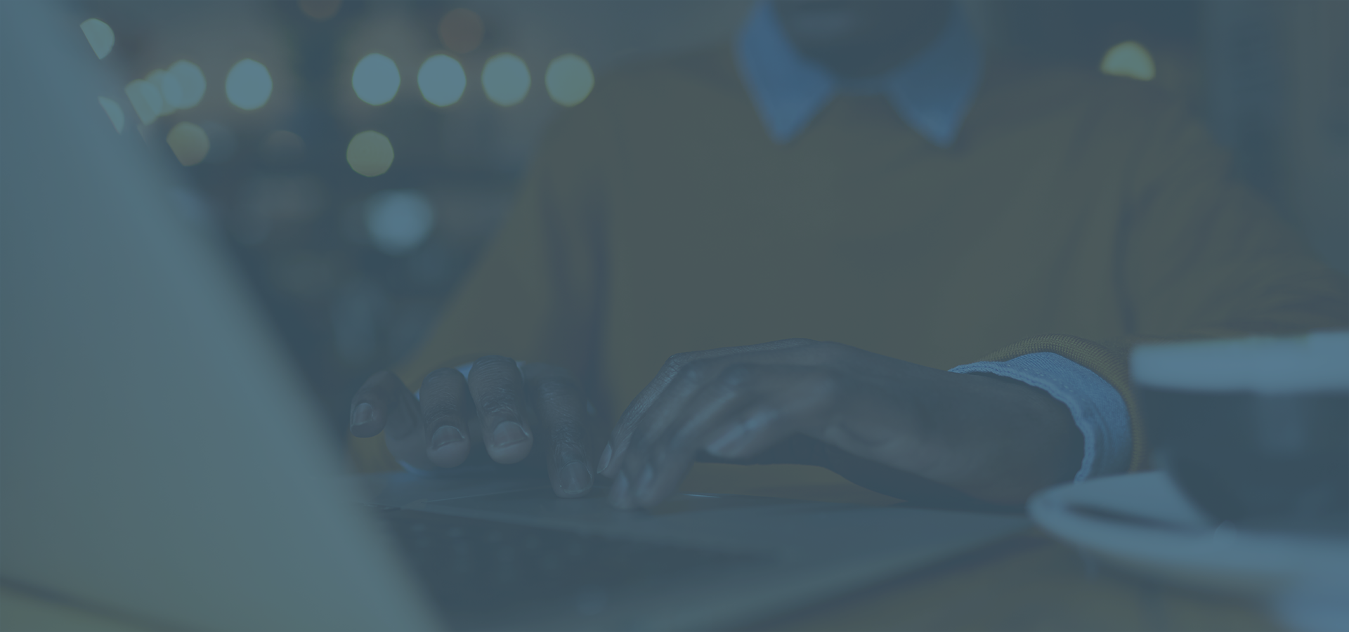 African-american man typing on keyboard in a coffee shop with a blue overlay.